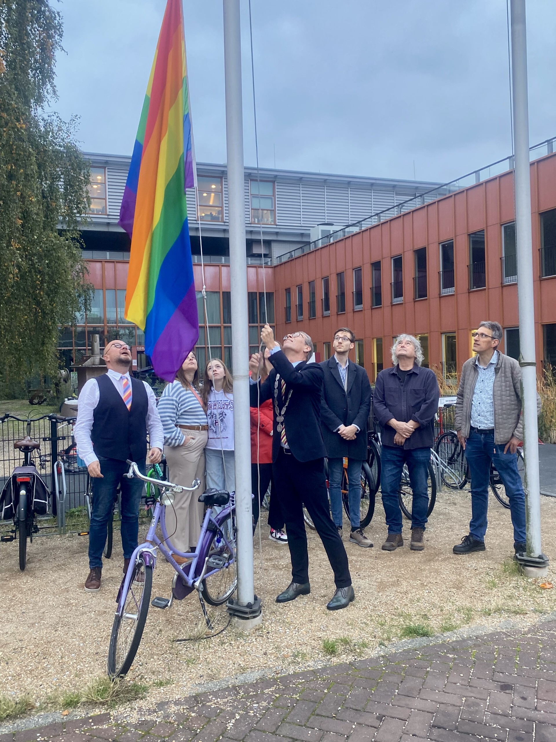 Burgemeester en wethouder hijsen regenboogvlag